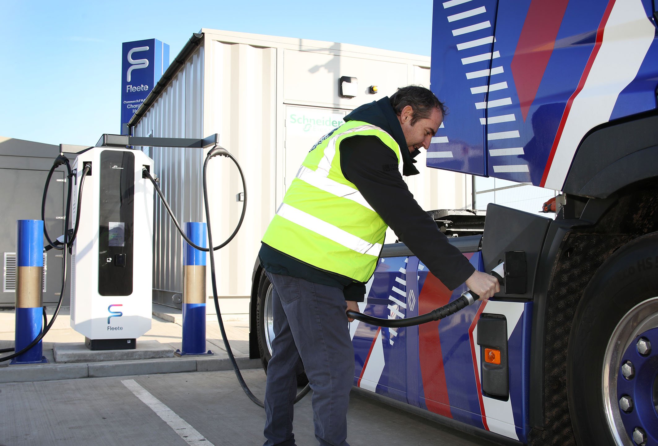 Person in high vis charges their electric heavy goods vehicle.