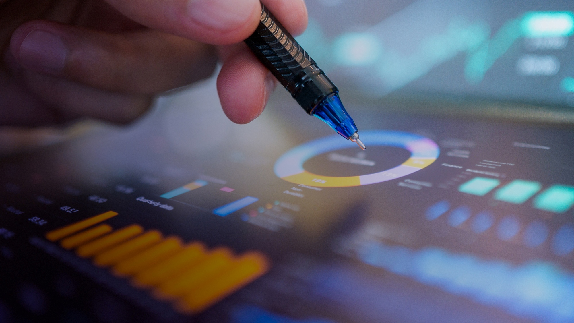 A close up of a hand holding a pen above a dashboard containing energy data