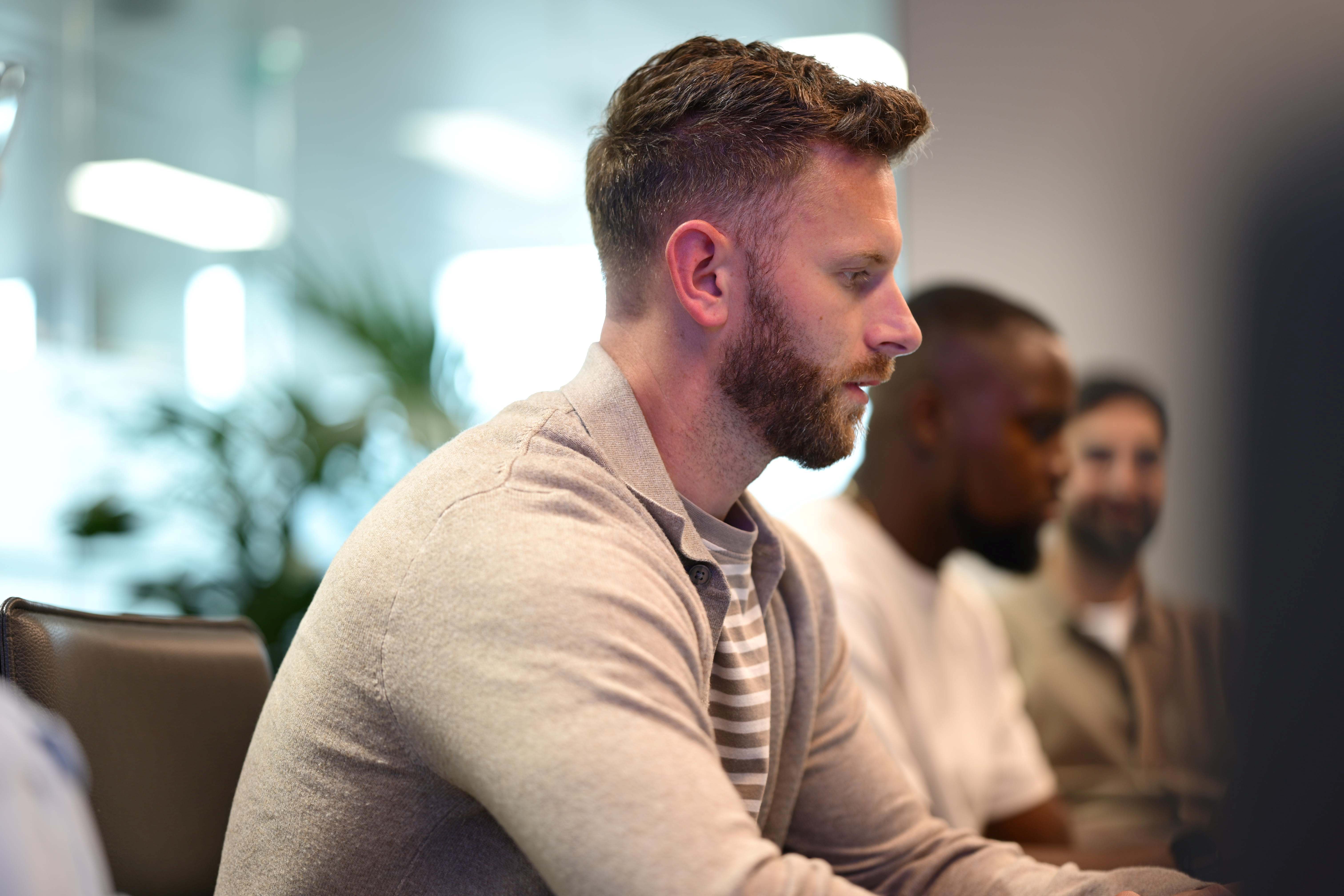 Three people sit in a row looking at laptops with focused expressions.
