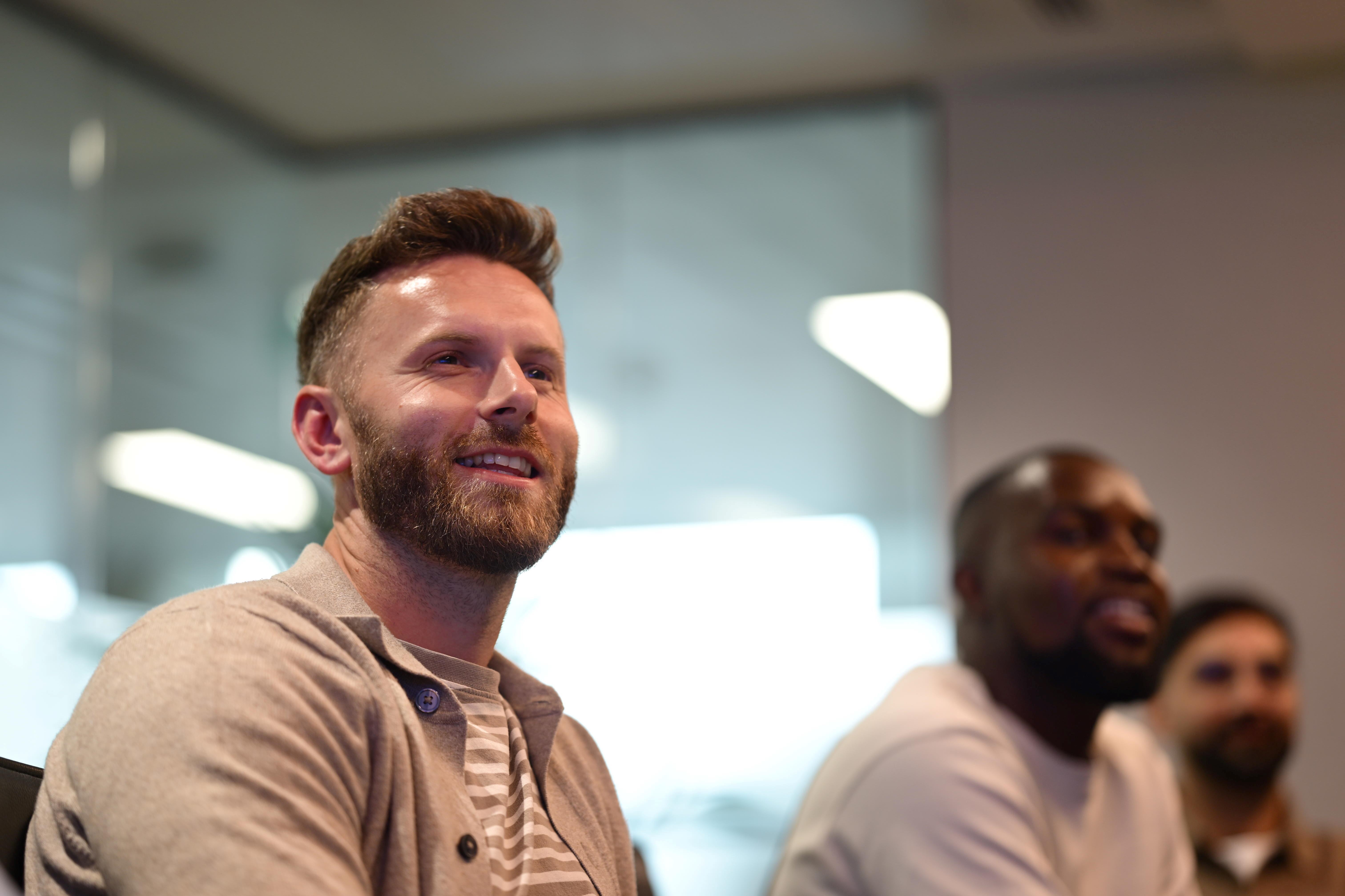 Three people sat at a table smile as they look off to the side.