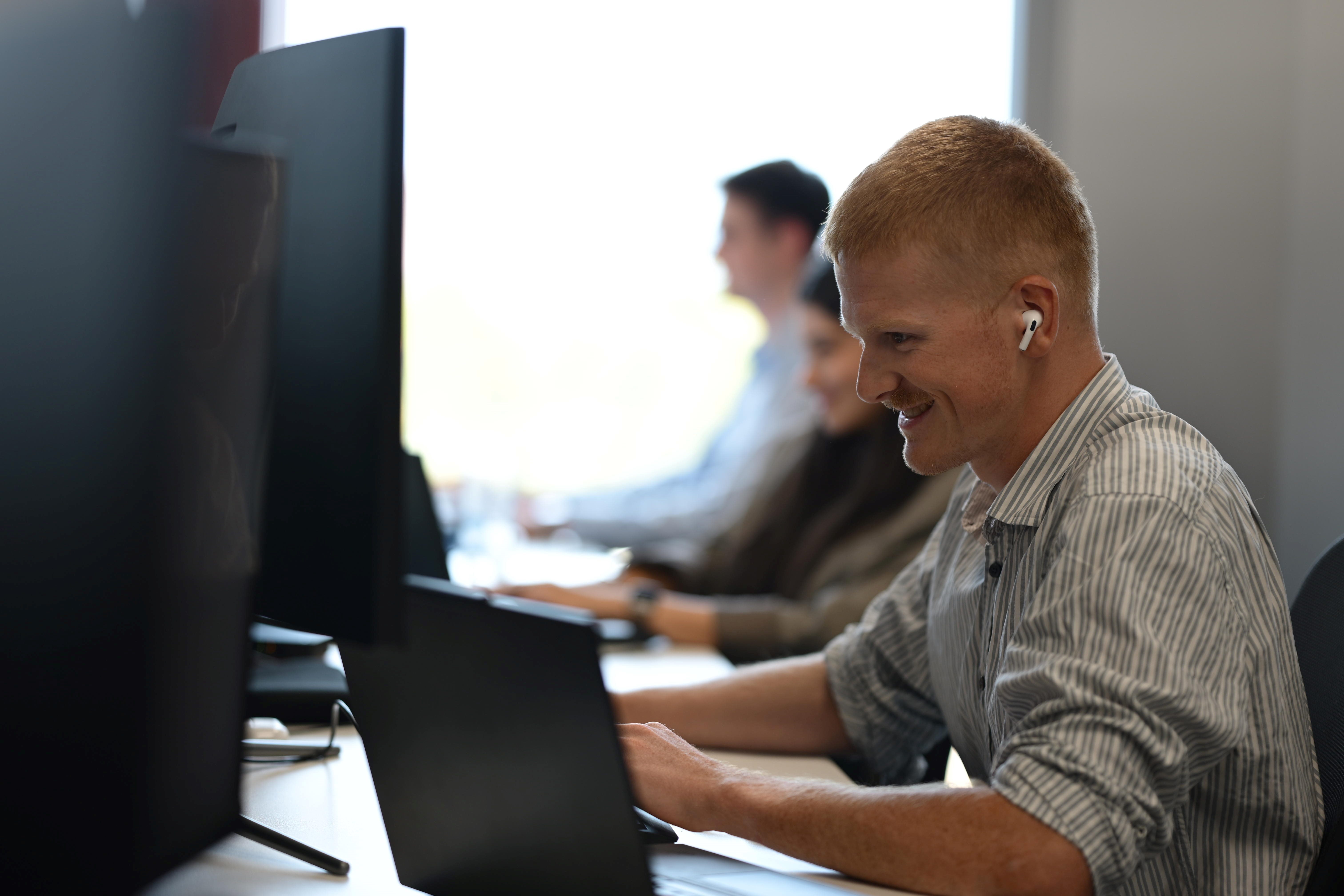 A person with earphones looks at a computer screen.