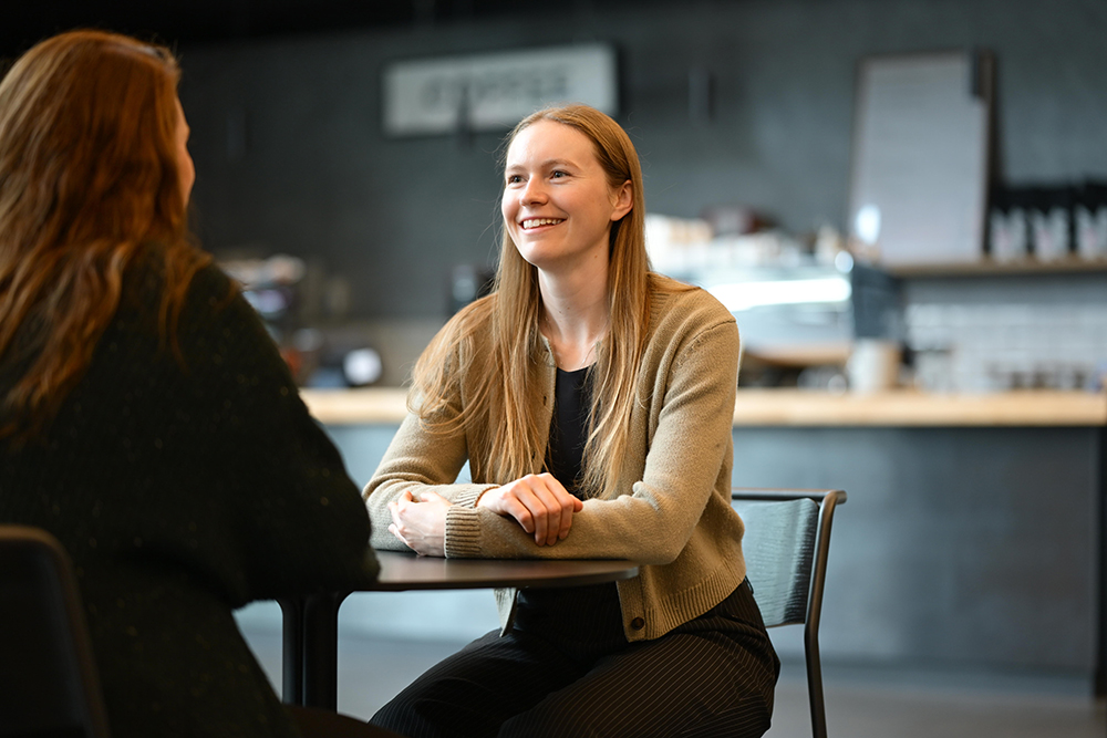 Two people sit at a table in a cafe.