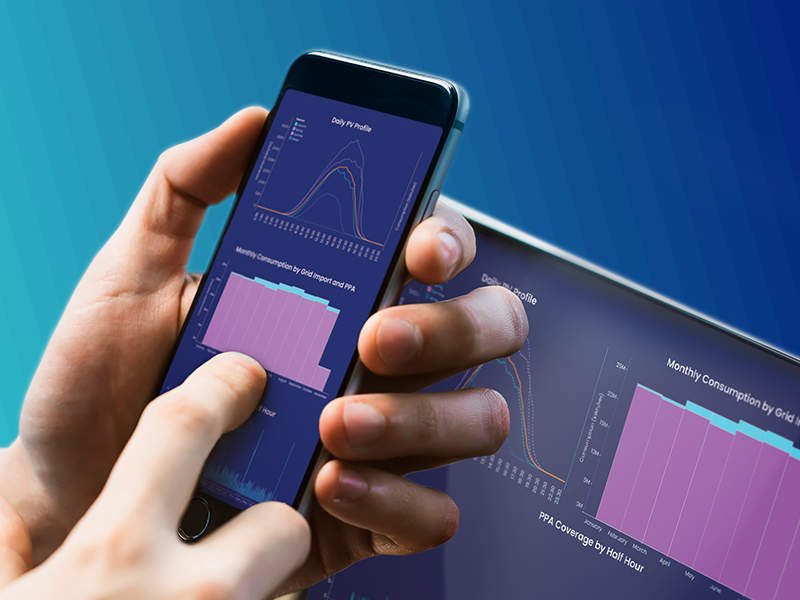 Hand holding a smartphone displaying energy-usage data, with a laptop against a turquoise gradient background showing similar analytics.