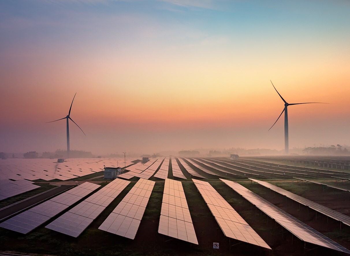 A field of solar panels set against a glowing sunset.