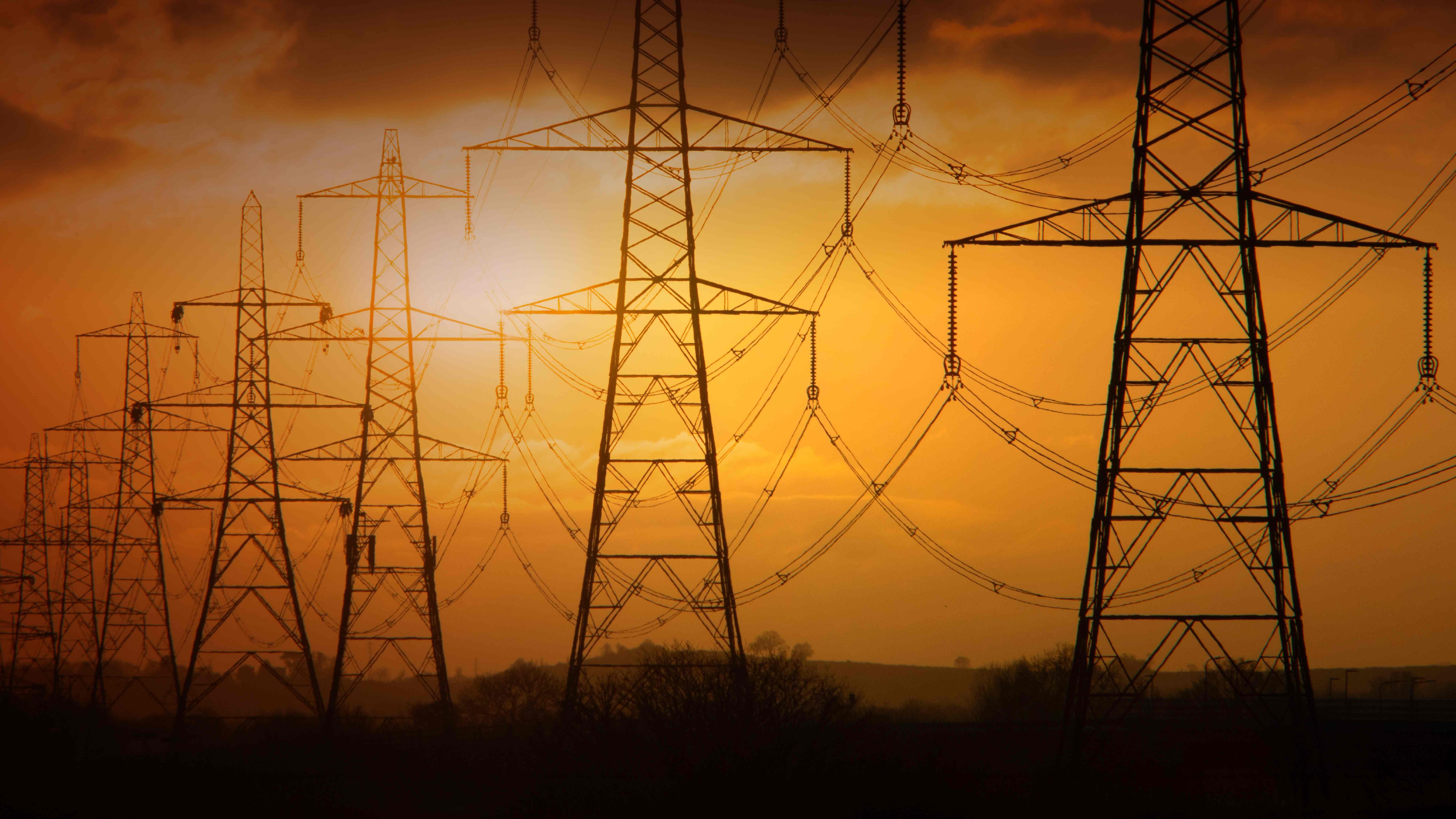 Electricity pylons set against a glowing sunset.