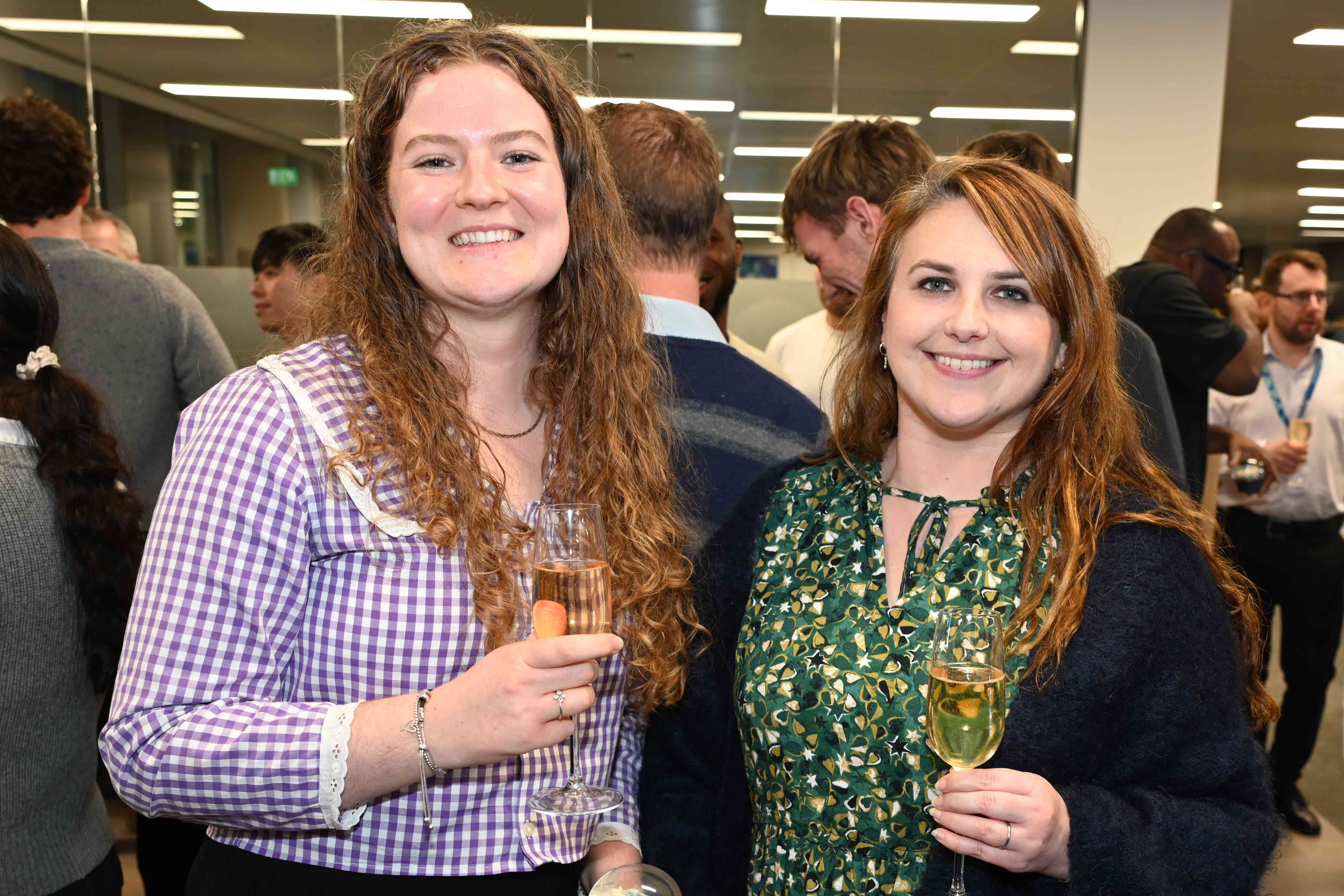 Two people stand for the camera and smile, with drinks