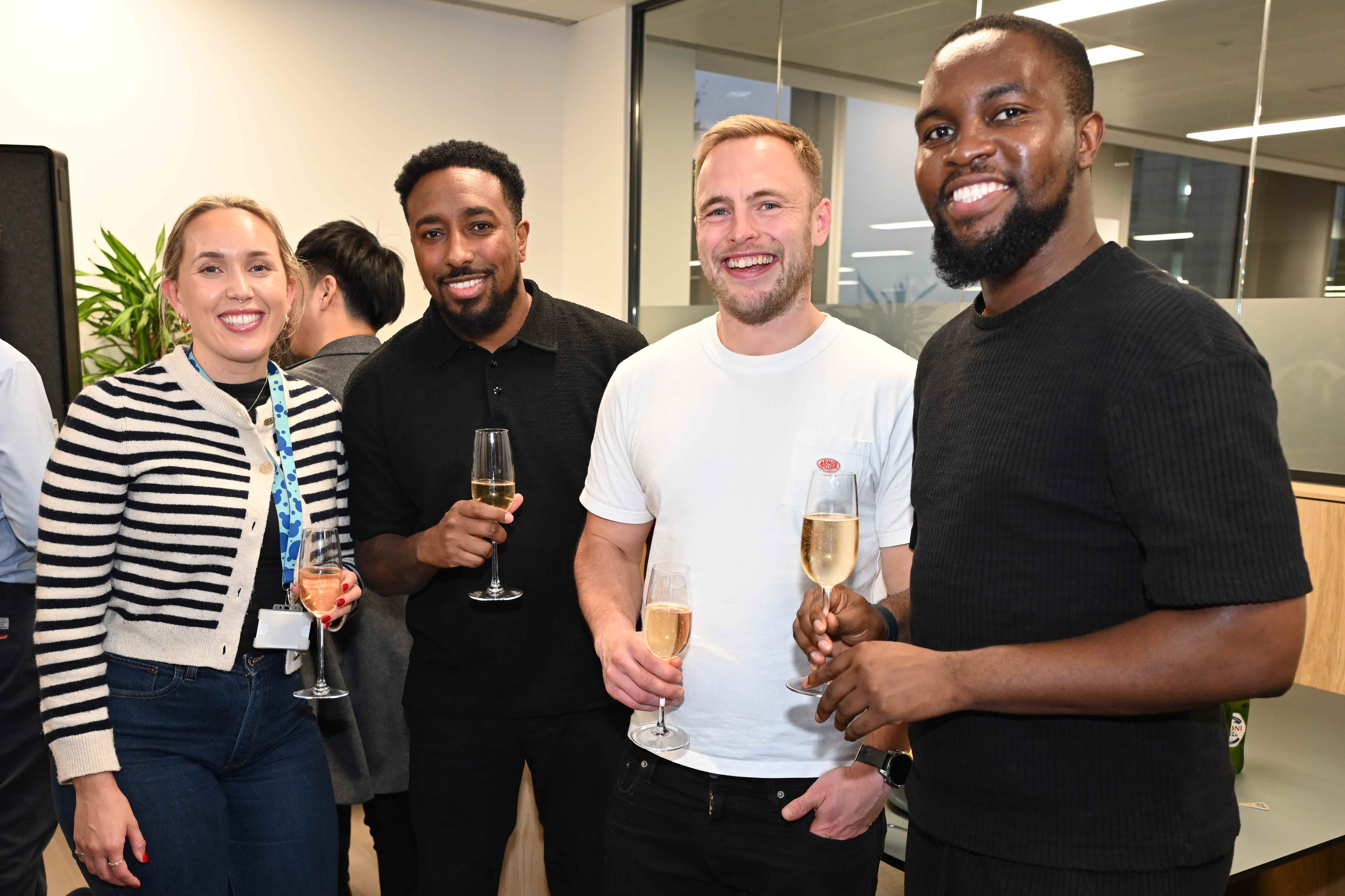 Four people pose for the camera with drinks