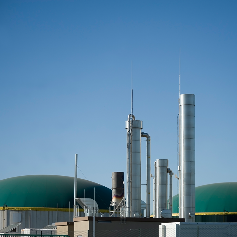 A side view of an anaerobic digestion plant set against a clear blue sky.