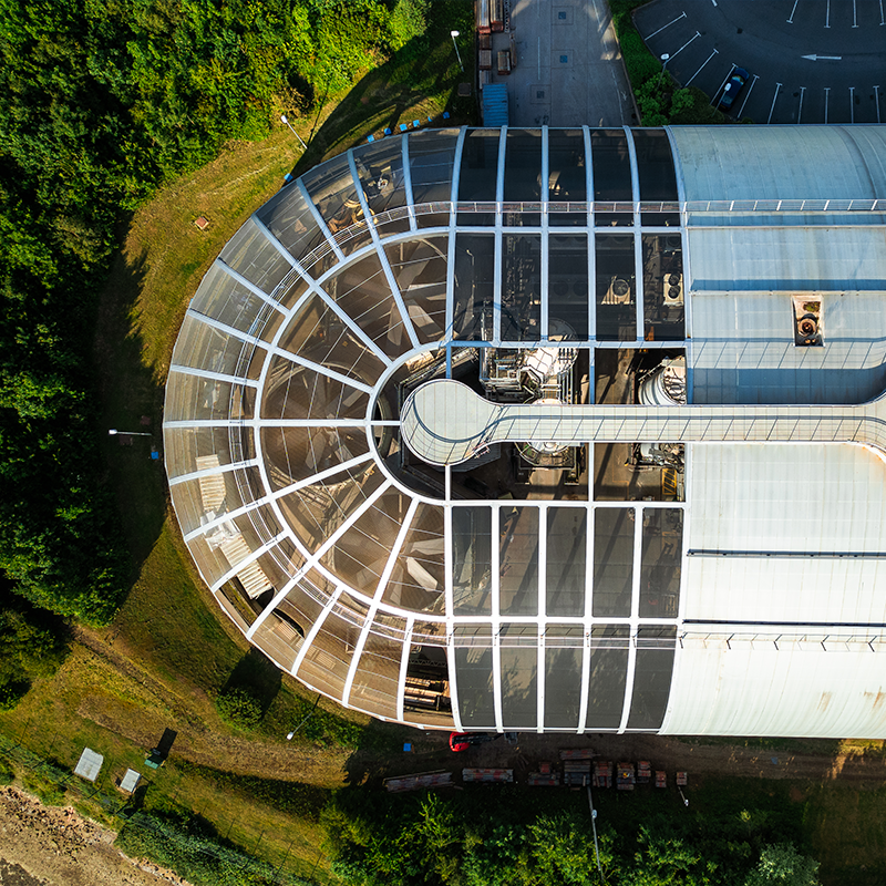 A birdseye view of a waste-to-energy plant, surrounded by green trees.