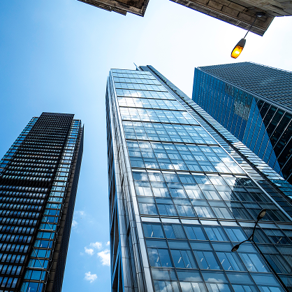A view from below of some towering skyscrapers against a blue sky.