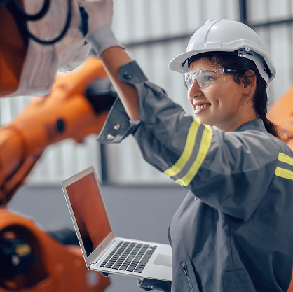 A person in goggles and a white hard hat adjusting something on a piece of machinery.
