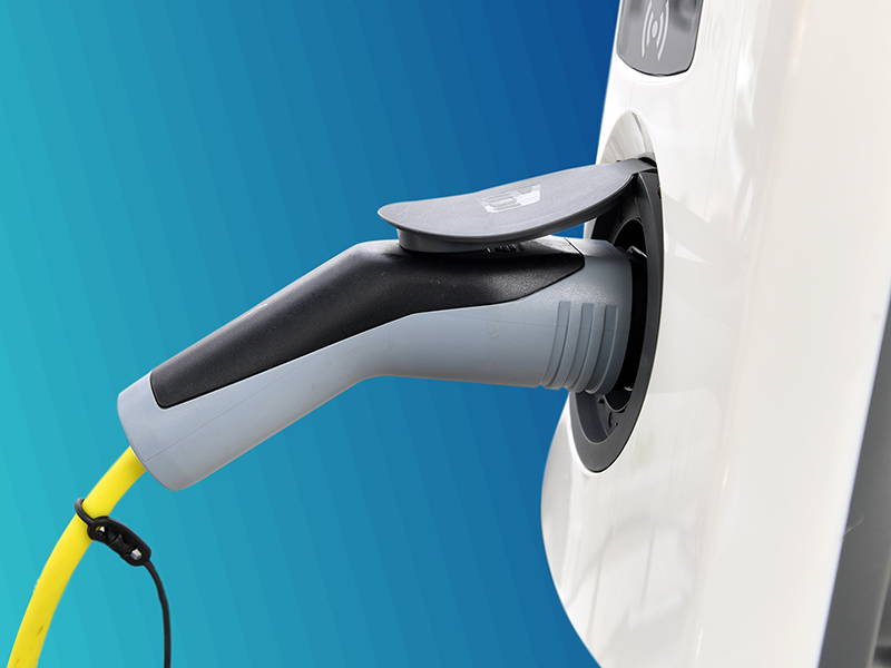 An electric charging point against a turquoise gradient background.