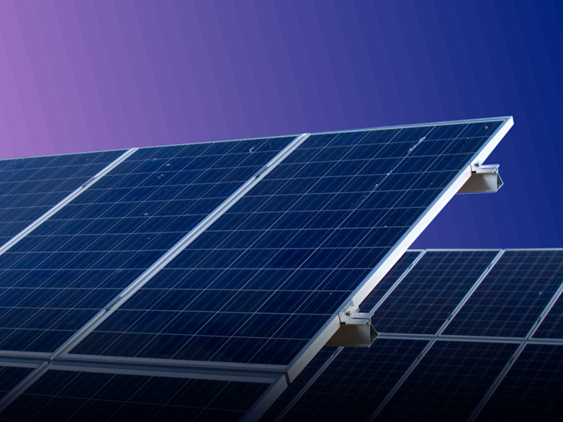 A close up of a solar panel against a pinkish gradient background.